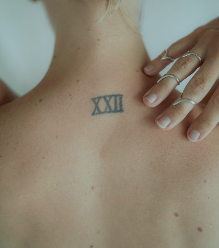 Mano donna con anelli, tattoo numeri romani, tatuaggio sulla schiena donna