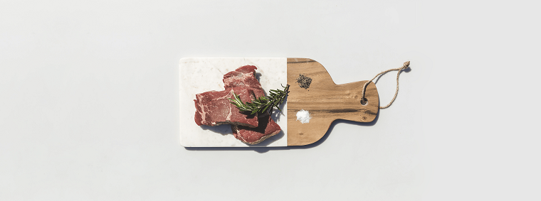 Foto di carne, costine di maiale con rosmarino, tagliere di legno, mucchietto di sale e pepe