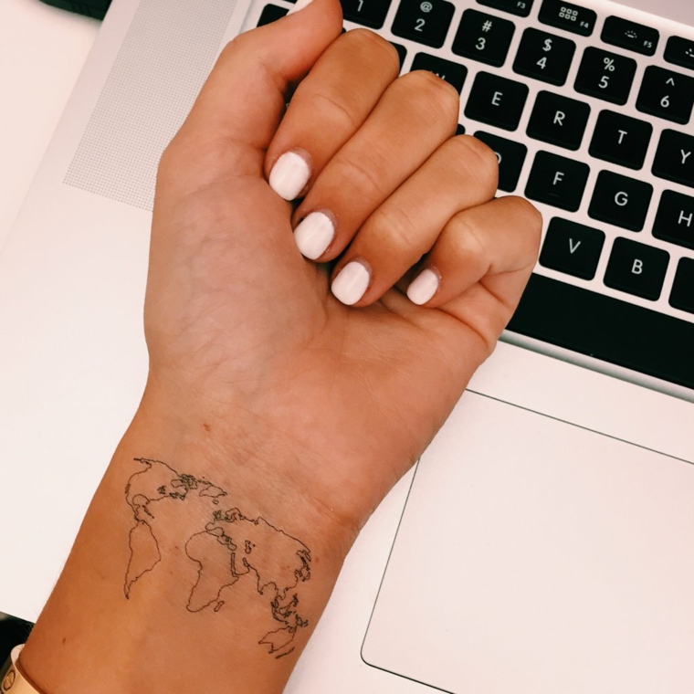 Tatuaggio mondo, tattoo sul polso, smalto unghie bianche, tastiere di un pc