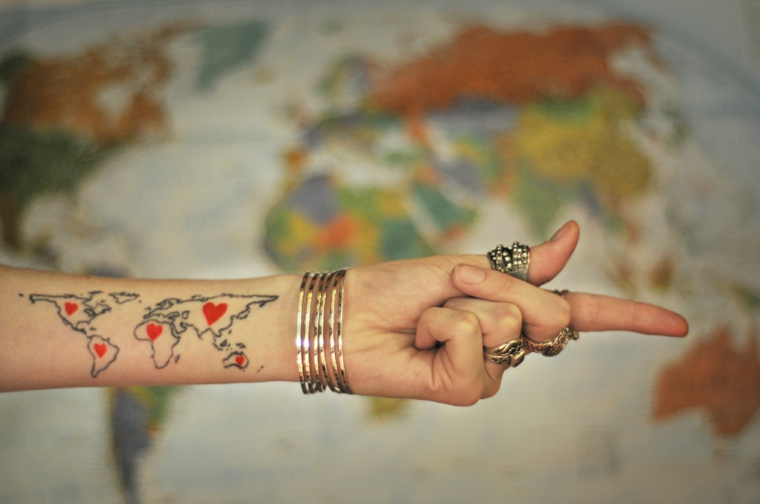 Tatuaggi colorati, tatuaggio sull'avambraccio, donna con braccialetti, mappamondo con cuori rossi