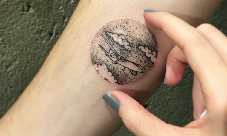 Tattoo pianeta terra, disegno nuvole e aereo, tatuaggio sull'avambraccio