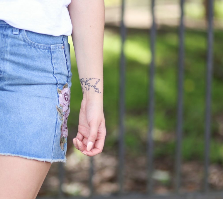 Tipi di tatuaggi, tattoo sul polso della mano, tattoo mappamondo, donna con gonna in jeans