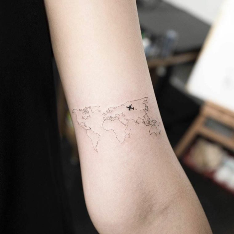 Tatuaggi colorati, tattoo sul braccio di una donna, disegno mappamondo e aereo
