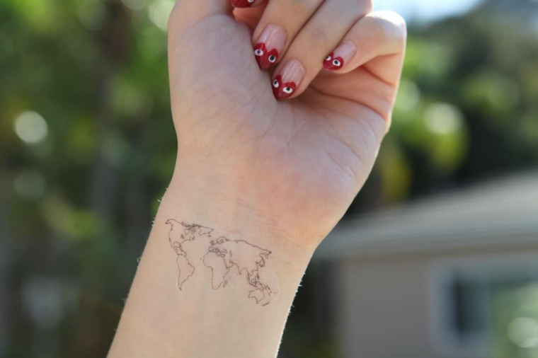 Tattoo sul polso, tatuaggio mondo, disegno continenti, unghie con smalto rosso