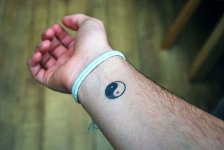 Tattoo yin yang, tatuaggio sul polso della mano, uomo con braccio tatuato