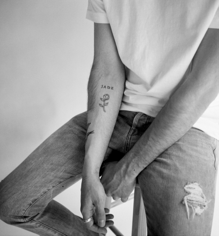 Tatuaggi scritte, tatuaggio sull'avambraccio, disegno tattoo rosa, uomo seduto su una sedia