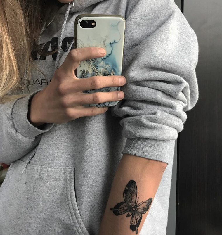 Farfalla significato, disegno di una farfalla sul braccio, ragazza con telefono in mano