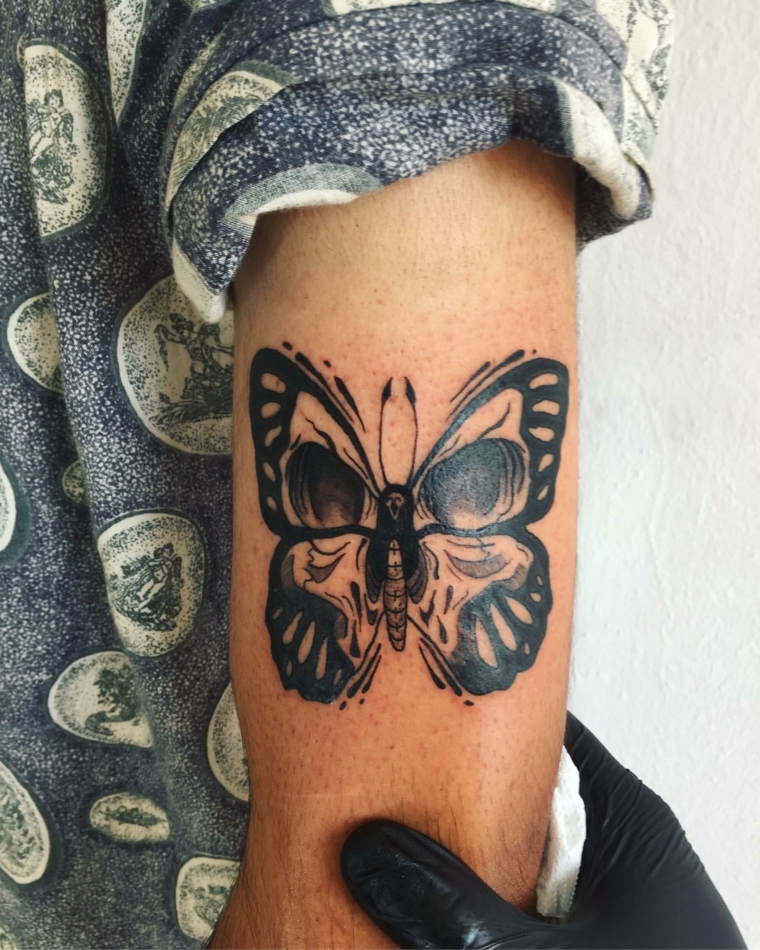 Uomo con tatuaggio di una farfalla di colore nero, uomo con tattoo sul braccio