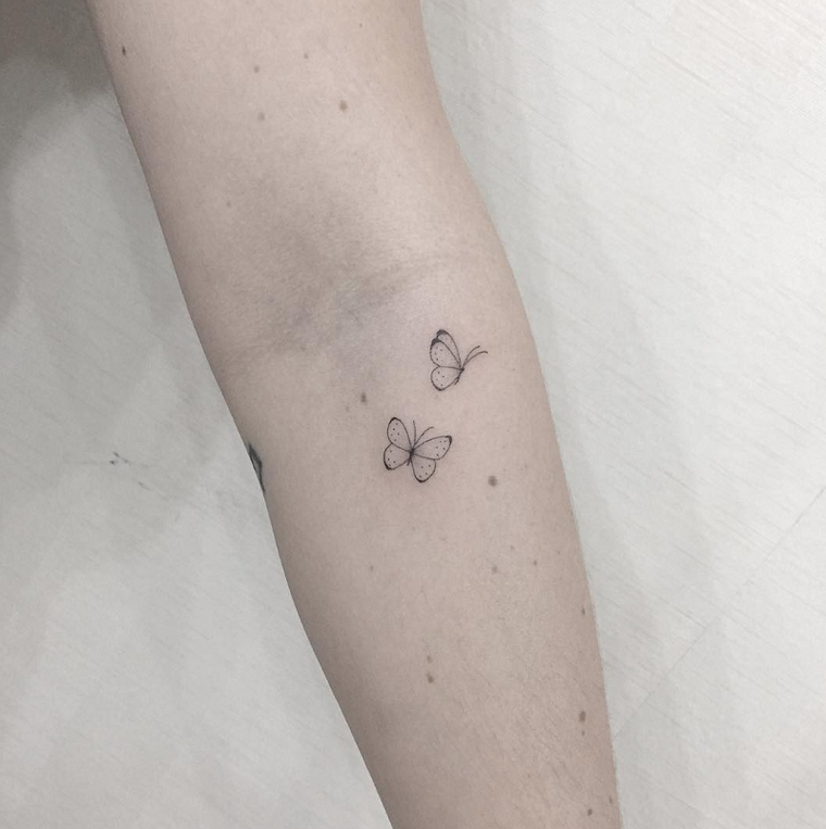 Piccolo tattoo sul braccio di una donna, disegno di farfalle come tatuaggio