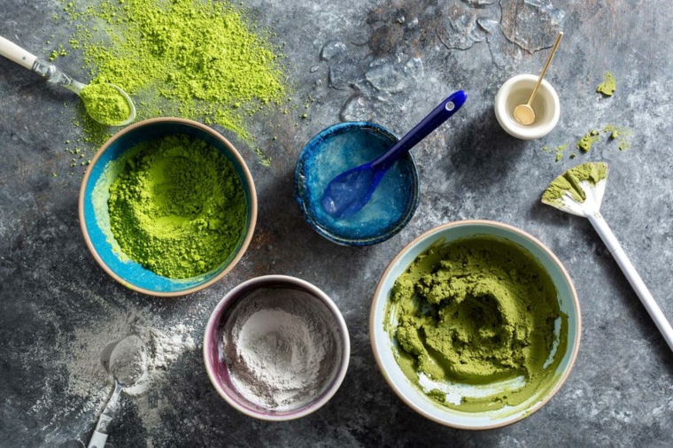 Ciotole con polvere di colore verde, ingredienti su un tavolo per maschera viso