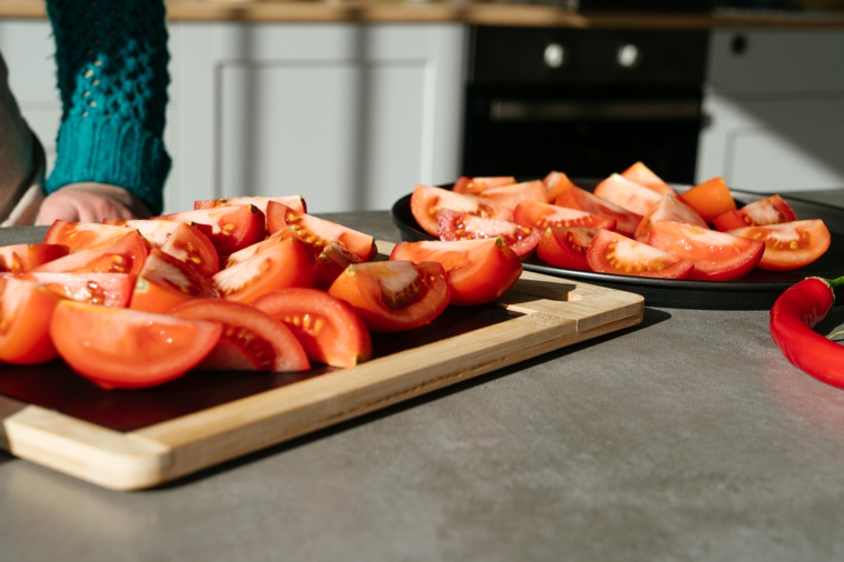 Tagliare di legno con pomodori tagliati a fette, ricette estive veloci ed economiche