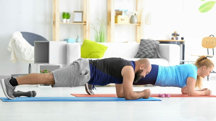 Uomo e donna in posizione di plank, allenamento in soggiorno, workout a casa