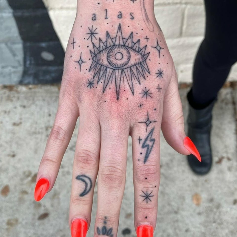 Tatuaggio illuminati, tatuaggio occhio e stelle sulla mano di una donna