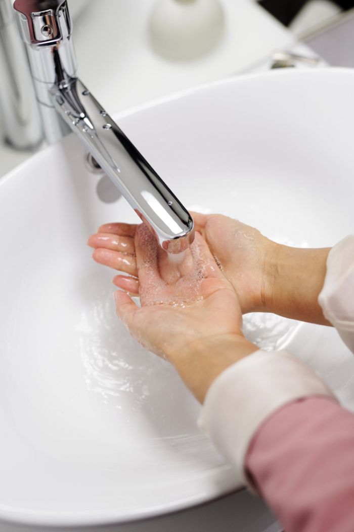 Disinfettante per le mani fatto in casa, donna che si lava le mani sotto l'acqua con sapone