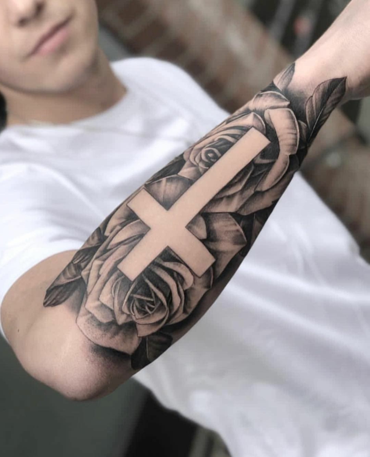 avambraccio di un ragazzo con tatuaggio disegno rose e croce tattoo sul braccio uomo