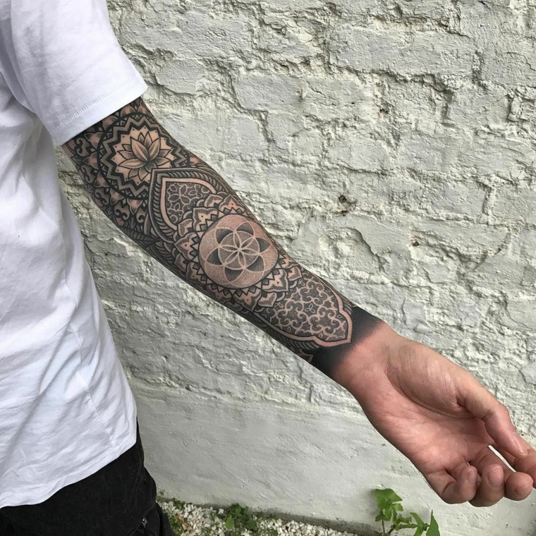braccio e avambraccio di un uomo con tatuaggio a manica con disegni motivi mandala