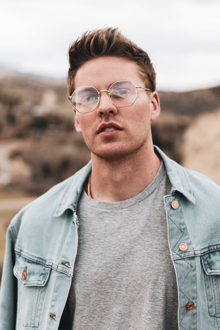 occhiali da vistra trasparenti uomo forma arrotondata giacca jeans capelli castani