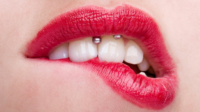 ragazza con rossetto rosso piercing gengiva donna con denti bianchi