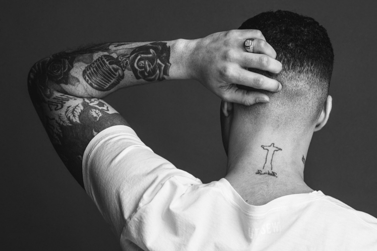 tatuaggio bracciale uomo disegno croce sul collo ragazzo con maglietta bianca