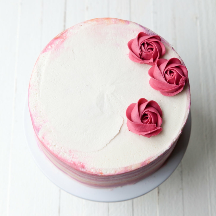 decorazione torta con fiorellini rosa base dolce di colore bianco