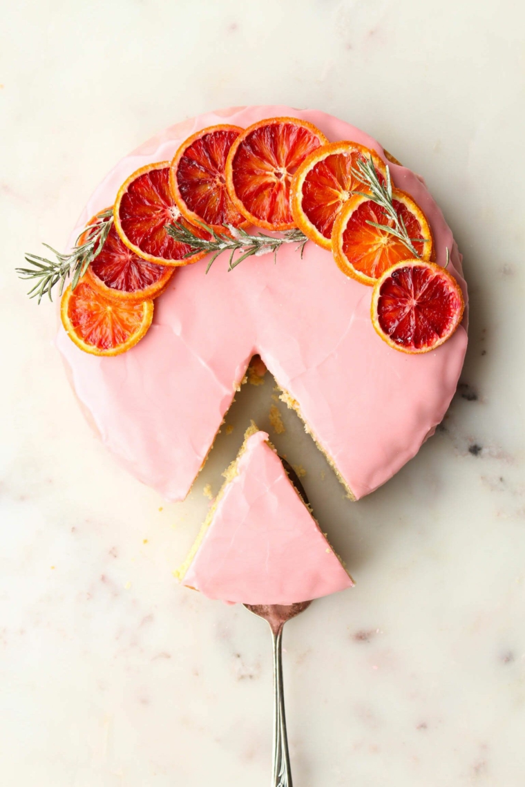 torta rotonda decorata con glassa rosa fette di arancia secche e rametti