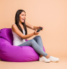 full size profile photo of optimistic brunette girl sit pouf with playstation wear top jeans isolated on beige background