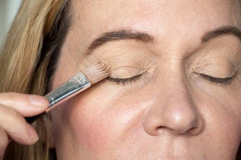 donna applica primer occhi trucco viso over 50
