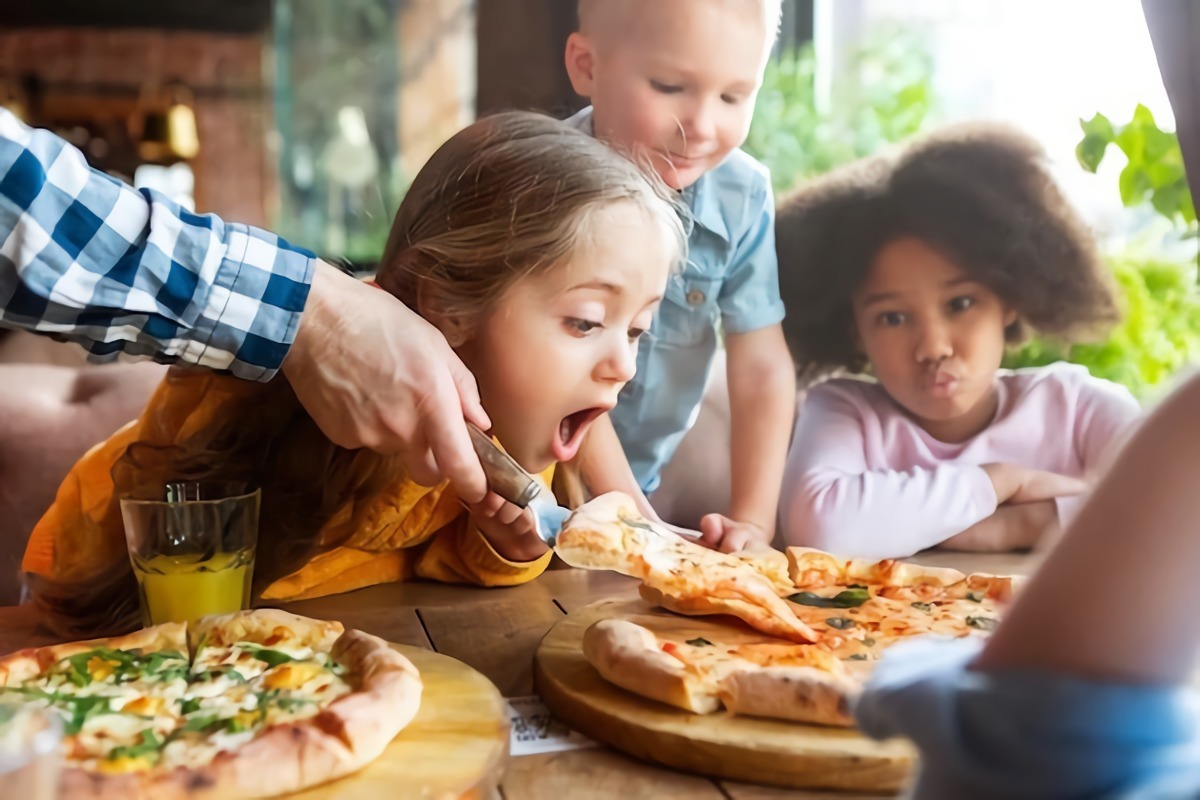 bambini che festeggiano compleanno mangiare la pizza in pizzeria