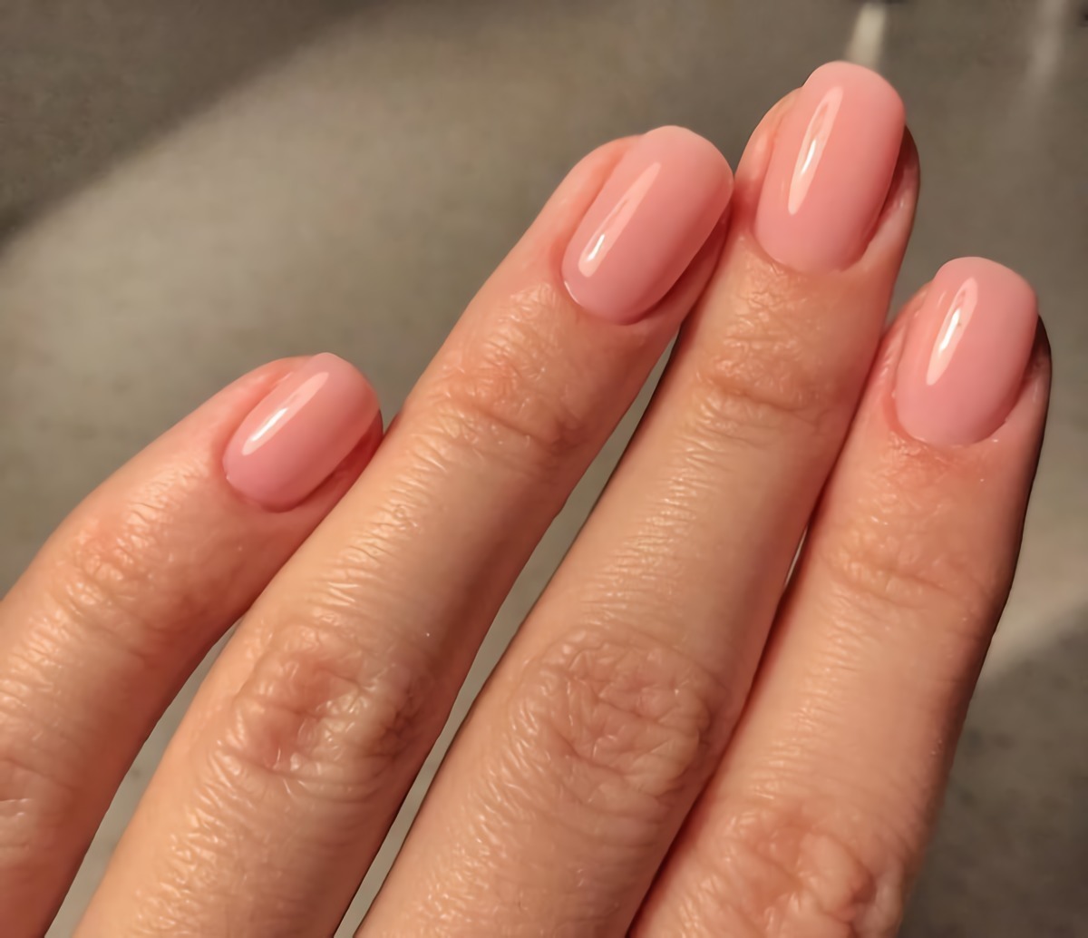 mani donna con unghie corte smalto colore rosa pallido