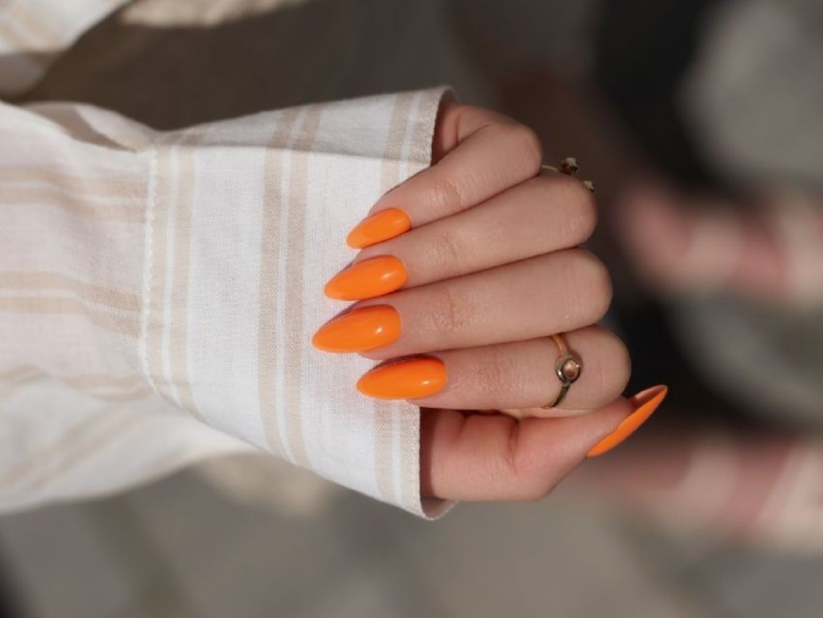 unghie arancioni anelli in oro camicia da donna