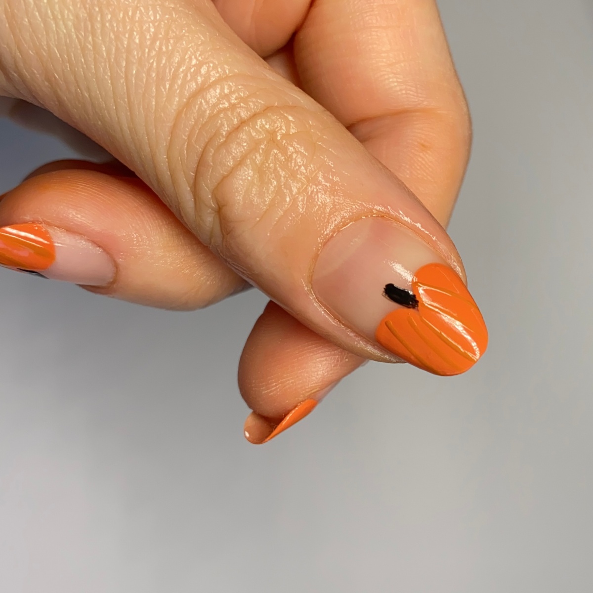 unghie color zucca con disegno smalto trasparente come base