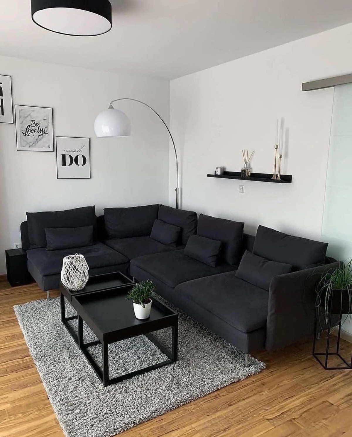 divano nero in soggiorno piccolo con pareti bianche